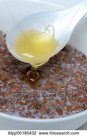 Stock Image - Bowl of swollen flax seed and spoonful of honey, flax swollen in water and milk, Common flax ( Linum usitatissimum). Fotosearch