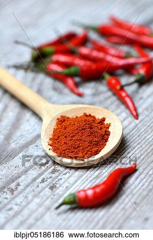 Stock Photograph - Chili, chili powder in wooden spoons and chili peppers ( Capsicum annuum). Fotosearch