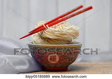 Stock Photo - Chinese Yangchun noodles in bowl with chopsticks, uncooked, nest noodles. Fotosearch