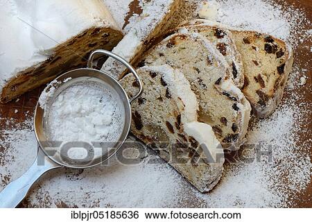 Stock Photograph - Christmas stollen and sieve with icing sugar. Fotosearch