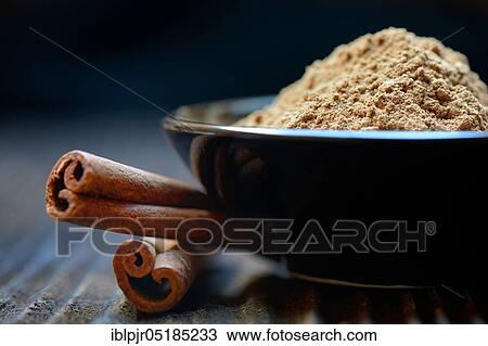 Stock Image - Cinnamonpowder ( Cinnamomum) in bowl and bars spec. Fotosearch