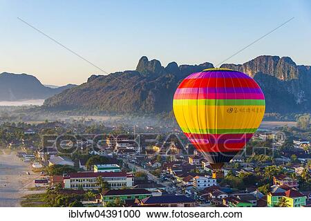 Colorful hot air balloon drifts over the city, karst mountains behind, Cityscape, Vang Vieng, Vientiane Province, Laos, Asia View Large Photo Image Stock Image - Colorful hot air balloon drifts over the city, karst mountains behind, Cityscape, Vang Vieng, Vientiane Province, Laos, Asia. Fotosearch