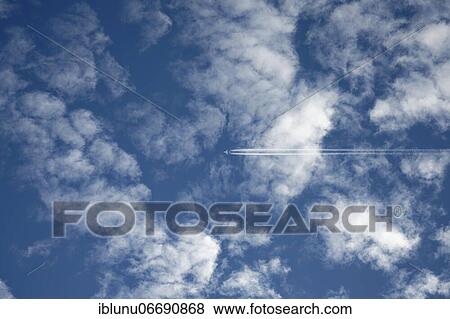 Commercial airplane with condensation trails in blue cloudy sky, Bern, Switzerland, Europe View Large Photo Image Stock Photo - Commercial airplane with condensation trails in blue cloudy sky, Bern, Switzerland, Europe. Fotosearch