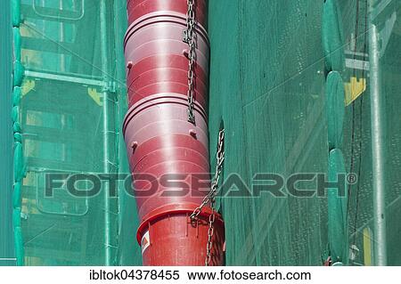 Stock Photography - Construction site, downpipe for rubble, façade of building covered in green tarpaulin, city centre, Lübeck, Germany, Europe. Fotosearch