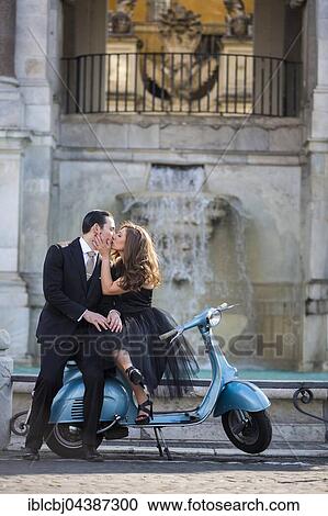 Stock Image - Couple kissing while sitting on a vespa scooter. Fontana dell'Acqua Paola, Il Fontanone, Gianicolo Hill, Janiculum Hill, Rome, Italy, Europe. Fotosearch