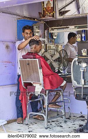 Stock Image - Customer at barber shop, man having hair cut, Bera, Rajasthan, India, Asia. Fotosearch