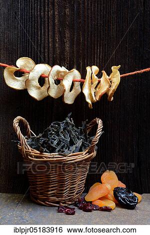 Stock Photograph - Dried fruit, apple rings in baskets, apple rings on string, apricots, prunes, cranberries and dried beans. Fotosearch