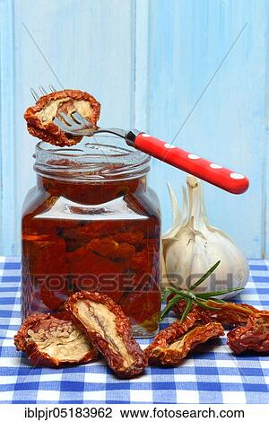 Stock Image - Dried tomatoes in jar with olive oil, antipasti, olive oil. Fotosearch