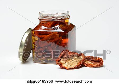 Stock Photograph - Dried tomatoes in jar with olive oil, antipasti, olive oil. Fotosearch