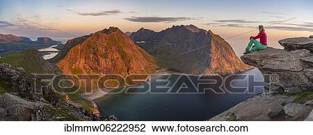 Stock Image - Evening atmosphere, hiker on top of Ryten, sea, Kvalvika beach and mountains, Fredvang, Lofoten, Nordland, Norway, Europe. Fotosearch