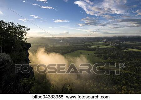 Fog is arising over the hills of Elbsandsteingebirge, seen from Lilienstein in the last light of the day, Königstein, Saxony, Germany, Europe View Large Photo Image Stock Photography - Fog is arising over the hills of Elbsandsteingebirge, seen from Lilienstein in the last light of the day, Königstein, Saxony, Germany, Europe. Fotosearch