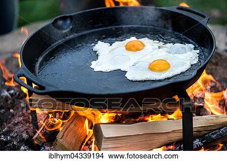 Picture - Fried eggs in a pan over an open fire. Fotosearch