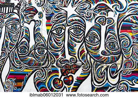 Stock Image - Graffiti We are one people, mural with colorful faces, artist Shamil Gimayev, East Side Gallery, Friedrichshain, Berlin, Germany, Europe. Fotosearch