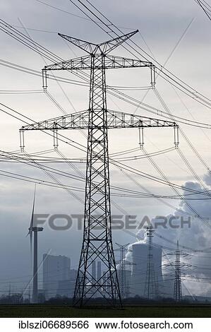 Stock Photograph - High-voltage electricity pylon or also overhead line pylon in front of the lignite-fired power plant Neurath, Grevenbroich, North Rhine-Westphalia, Germany, Europe. Fotosearch