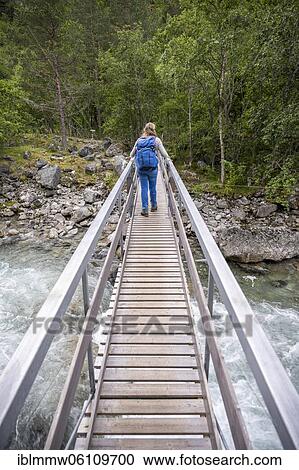Stock Image - Hiker on wooden bridge over the river Driva, Åmotan Gorge, Gjøra, Norway, Europe. Fotosearch
