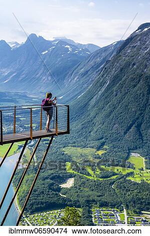 Picture - Hiker standing on viewing platform Rampestreken, hiking Romsdalseggen, river Rauma, Romsdalfjellene mountains, Andalsnes, Møre og Romsdal, Norway, Europe. Fotosearch