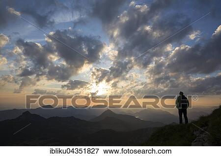 Stock Photo - Hikers looking in the distance, sunrise at Krottenkopf, Ester Mountains, overlooking the Simetsberg, Herzogstand, Benediktenwand, Garmisch-Partenkirchen District, Bavaria, Germany, Europe. Fotosearch
