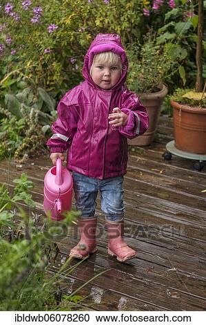 Little girl with rubber boots and rain jacket playing with water and watering can in the rain, Upper Bavaria, Bavaria, Germany, Europe View Large Photo Image Stock Image - Little girl with rubber boots and rain jacket playing with water and watering can in the rain, Upper Bavaria, Bavaria, Germany, Europe. Fotosearch