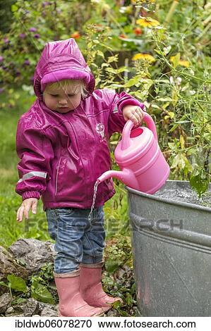 Little girl with rubber boots and rain jacket playing with water and watering can in the rain, Upper Bavaria, Bavaria, Germany, Europe View Large Photo Image Stock Image - Little girl with rubber boots and rain jacket playing with water and watering can in the rain, Upper Bavaria, Bavaria, Germany, Europe. Fotosearch