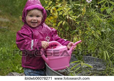 Little girl with rubber boots and rain jacket playing with water and watering can in the rain, Upper Bavaria, Bavaria, Germany, Europe View Large Photo Image Stock Image - Little girl with rubber boots and rain jacket playing with water and watering can in the rain, Upper Bavaria, Bavaria, Germany, Europe. Fotosearch