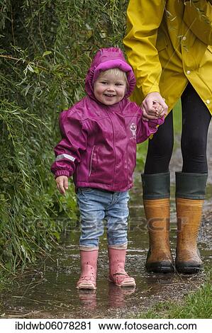 Little girl with rubber boots and rain jacket holding her mother's hand in the rain, in bad weather, Upper Bavaria, Bavaria, Germany, Europe View Large Photo Image Stock Image - Little girl with rubber boots and rain jacket holding her mother's hand in the rain, in bad weather, Upper Bavaria, Bavaria, Germany, Europe. Fotosearch