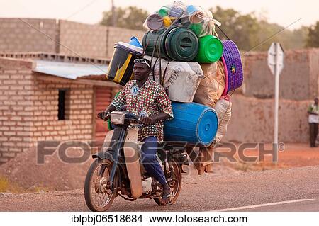 Picture - Loaded motorcycle with driver, flying trader, Bobo-Dioulasso, Burkina Faso, Africa. Fotosearch