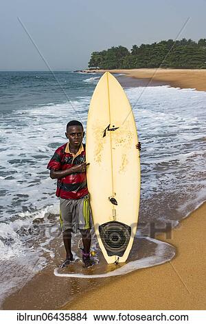 Local boy with his surfboard on a beach in Robertsport, Liberia, Africa View Large Photo Image Picture - Local boy with his surfboard on a beach in Robertsport, Liberia, Africa. Fotosearch