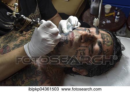 Stock Image - Man, Arab gets tattooed on his chin, Ko Samui, Thailand, Asia. Fotosearch