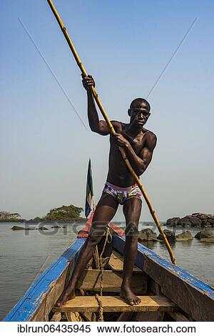 Stock Photography - Man pushing his small boat on Banana islands, Sierra Leone, Africa. Fotosearch
