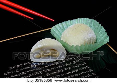 Stock Photograph - Mochi with chopsticks, Japanese sticky rice cake with green tea taste, Asian confectionery speciality. Fotosearch