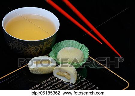 Stock Image - Mochis with tea and chopsticks, Japanese sticky rice cake with green tea flavour, Asian confectionery speciality. Fotosearch