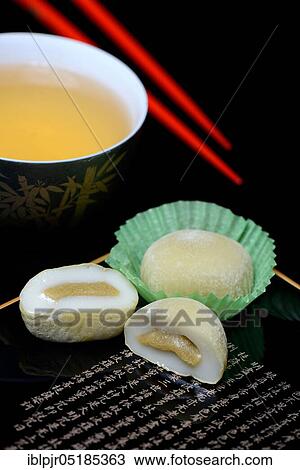 Stock Image - Mochis with tea and chopsticks, Japanese sticky rice cake with green tea flavour, Asian confectionery speciality. Fotosearch