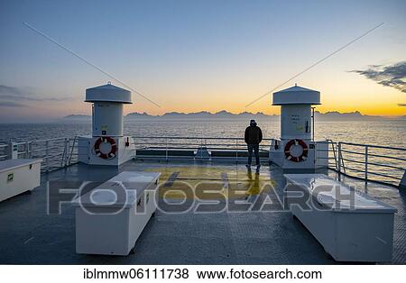 Passenger looking over the ocean, evening mood on ferry in front of silhouette of mountains, Lofoten, Nordland, Norway, Europe View Large Photo Image Stock Photo - Passenger looking over the ocean, evening mood on ferry in front of silhouette of mountains, Lofoten, Nordland, Norway, Europe. Fotosearch