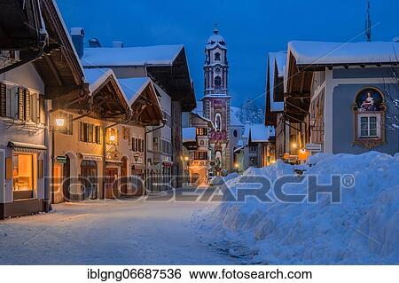 Stock Photograph - Pedestrian zone in the center with typical houses and parish church at dusk, Mittenwald, Werdenfelser Land, Upper Bavaria, Bavaria, Germany, Europe. Fotosearch