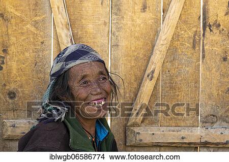 Picture - Portrait, elderly friendly woman in front of wooden door, Dolpo, Nepal, Asia. Fotosearch