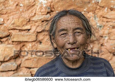 Stock Image - Portrait, friendly elderly woman in front of a house wall, Dolpo, Nepal, Asia. Fotosearch