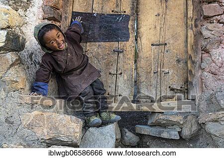 Stock Photograph - Portrait, small laughing boy in front of a wooden door, Saldang, Dolpo, Nepal, Asia. Fotosearch