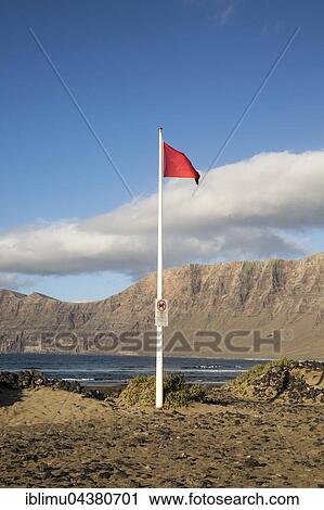 Red flag flying warning of bathing danger, La Caleta de Famara, Lanzarote, Canary islands, Spain, Europe View Large Photo Image Stock Image - Red flag flying warning of bathing danger, La Caleta de Famara, Lanzarote, Canary islands, Spain, Europe. Fotosearch