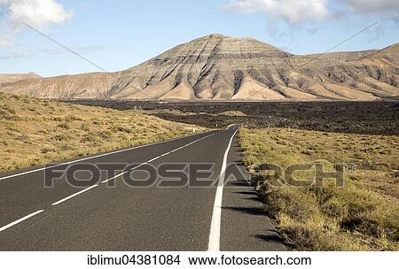Picture - Road leading towards volcanic landscape, Montana de Medio, Los Ajaches mountain range, Lanzarote, Canary Islands, Spain, Europe. Fotosearch