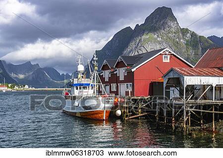 Stock Image - Rorbuer, typical wooden houses, fishing boat in harbour, Reine, Moskenesöy, Lofoten, Nordland, Norway, Europe. Fotosearch
