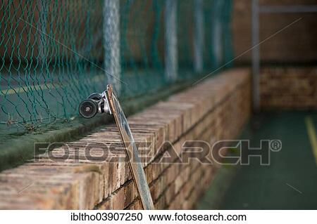 Stock Image - Skateboard leaning against a brick wall in tennis court yard. Fotosearch