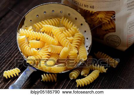 Stock Image - Spiral noodles in sieve ladle, Fusilli, uncooked. Fotosearch