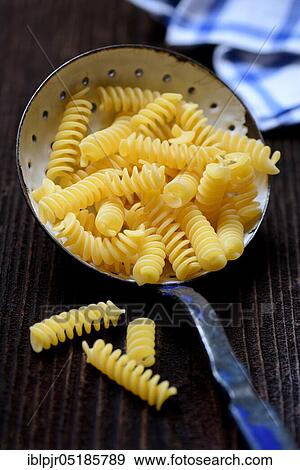 Stock Photo - Spiral noodles in sieve ladle, Fusilli, uncooked. Fotosearch