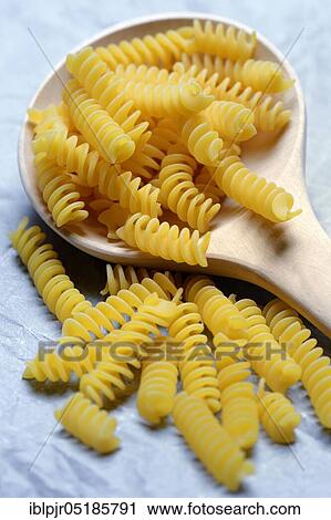 Stock Image - Spiral noodles in wooden ladle, Fusilli, uncooked. Fotosearch