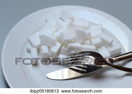 Stock Image - Sugar cubes on plate with cutlery, sugar consumption, sugar consumption. Fotosearch