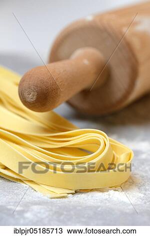 Stock Image - Tagliatelle, uncooked, pappardelle, pasta, ribbon noodles, rolling pin. Fotosearch