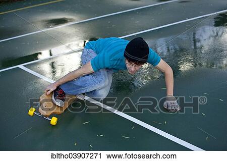 Teenage boy skating with his longboard in a tennis court yard View Large Photo Image Stock Image - Teenage boy skating with his longboard in a tennis court yard. Fotosearch