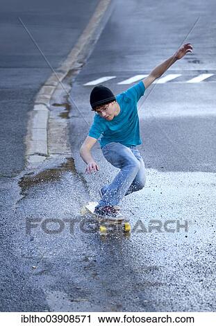 Teenager riding a longboard downhill on a wet street View Large Photo Image Stock Image - Teenager riding a longboard downhill on a wet street. Fotosearch