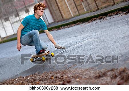 Teenager riding a longboard downhill on a wet street View Large Photo Image Stock Photo - Teenager riding a longboard downhill on a wet street. Fotosearch
