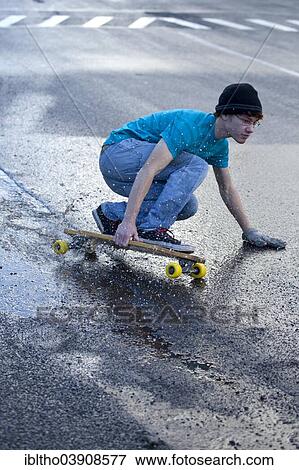 Teenager riding a longboard downhill on a wet street View Large Photo Image Stock Photo - Teenager riding a longboard downhill on a wet street. Fotosearch